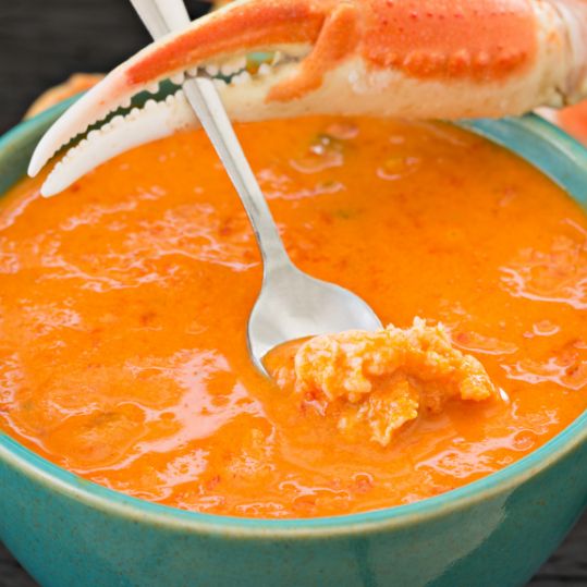 crab holding a spoon with crab bisque